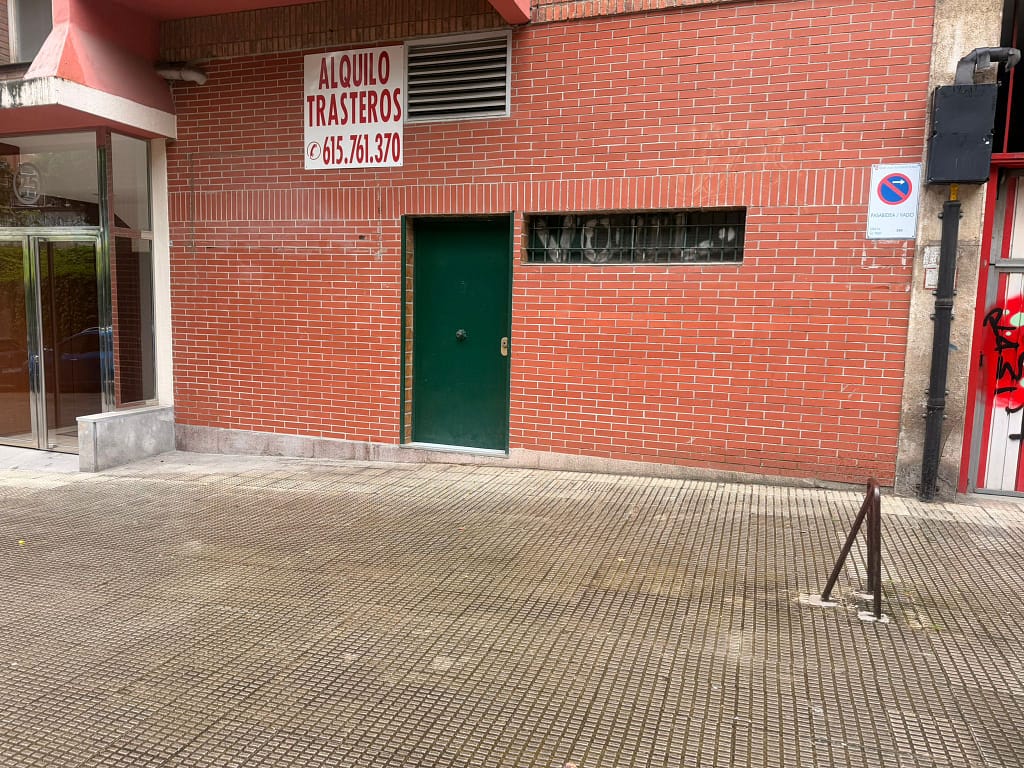 Fachada de un local comercial con puerta verde y revestimiento de ladrillo