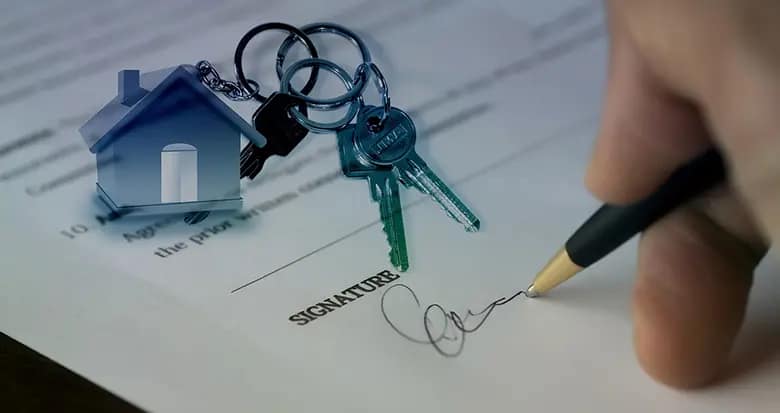 Persona firmando contrato de compra de vivienda.