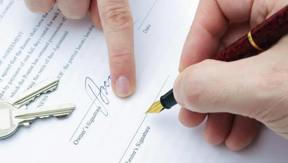 Es una imagen que muestra a una persona indicando a otra dónde firmar en un contrato.
